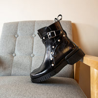 Black leather boot with a buckle on a gray chair